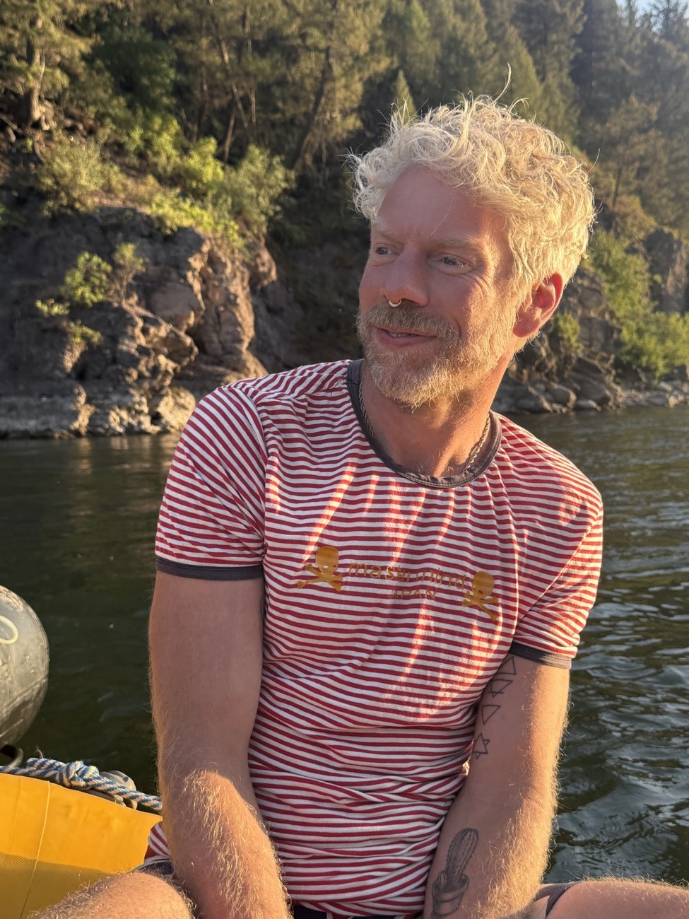 Riverside in a striped tee, golden hour light off the water