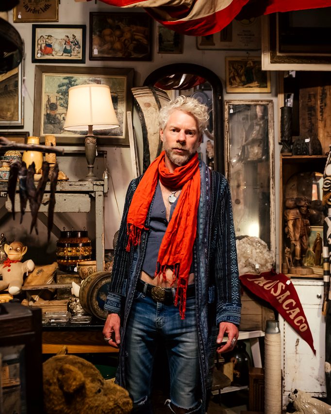 Seated inside a richly cluttered, eclectic shop